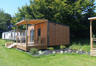 Prestige Cottage au Camping Seasonova Etennemare en France, chalet en bois avec terrasse et pelouse verte.
