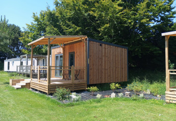 Prestige Cottage au Camping Seasonova Etennemare en France, chalet en bois avec terrasse et pelouse verte.