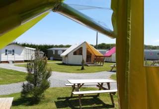 Vista da una tenda safari Ecolodge Junior con tavoli da picnic al Camping Seasonova Etennemare, Francia.