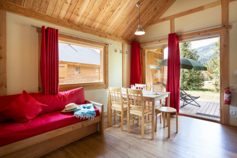 Interior view of Chalet Montana at Camping de l'Ill - Colmar, featuring wood furnishings and garden access.