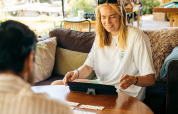 Young woman plays a board game with a friend inside a cozy glamping accommodation, smiling happily.