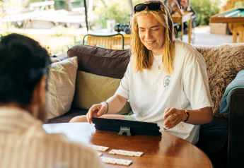 Jeune femme souriante joue à un jeu de société avec un ami dans un hébergement glamping confortable.
