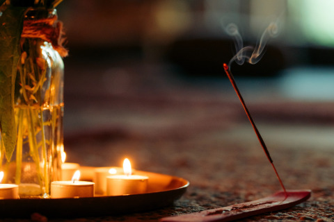 Ambiente acogedor en una tienda glamping con velas encendidas y varilla de incienso humeante en primer plano.