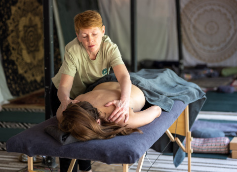 Een gast ontvangt een ontspannende massage in een sfeervol ingerichte glamping-accommodatie.