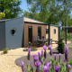 Moderne tiny house Forest lodge i Holiday Park 't Rheezerwold i Holland omgivet af grønne træer.