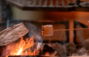 En skumfidus ristes over et lejrbål i komfortable omgivelser på en luksuriøs glamping indkvartering.