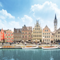 Fila de coloridos edificios históricos junto a un canal en Poperinge, Flandes Occidental, Bélgica, con cielo azul.