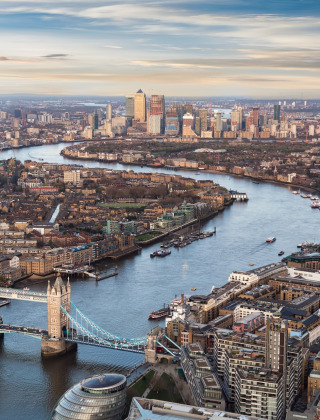 Udsigt over London med Tower Bridge og Themsen, med byens skyline og moderne bygninger i baggrunden.