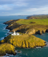Vista aérea de la costa cerca de Bala, Gales, Reino Unido, con un faro sobre un promontorio rocoso.