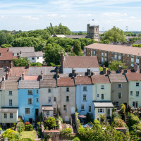 Filas de casas coloridas y jardines cerca de Bala, Gales, con una iglesia antigua en el fondo del paisaje.