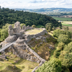 Vista aérea de las ruinas de un castillo histórico cerca de Bala, Gales, rodeado de campos verdes y bosques densos.