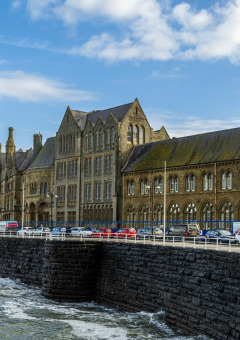 Edificio histórico en el paseo marítimo de Bala, Gales, Reino Unido, con olas rompiendo en el malecón.