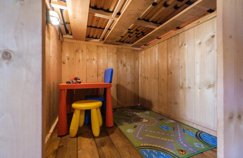 Holzspielzimmer für Kinder mit buntem Tisch, Stühlen und Teppich im GlampCamp Safari Tent, Camping De Klimberg.