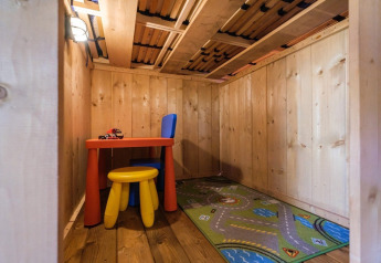 Indendørs børnelegeområde i træ med farverige møbler og tæppe i GlampCamp Safari Tent, Camping De Klimberg.