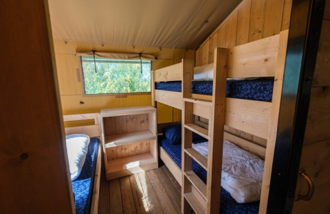 Innenraum des GlampCamp Safari Zelts mit Etagenbetten und Holzmöbeln auf Camping De Klimberg in den Niederlanden.