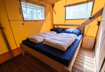 Intérieur de la tente safari GlampCamp au Camping De Klimberg, Pays-Bas, avec un lit confortable.