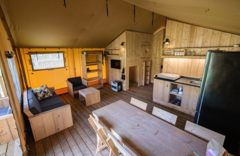 Vue intérieure de la tente GlampCamp Safari au Camping De Klimberg aux Pays-Bas avec mobilier en bois.