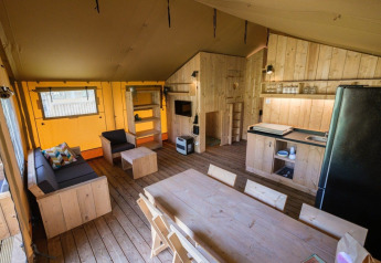Vista interior de la GlampCamp Safari Tent en Camping De Klimberg en los Países Bajos con muebles de madera.