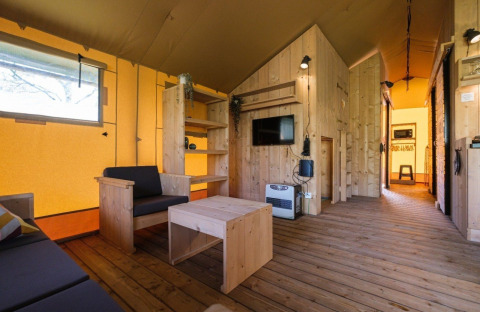 Vista interior de una tienda safari de lujo con muebles de madera en Camping De Klimberg, Países Bajos.
