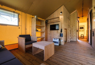 Vista interior de una tienda safari de lujo con muebles de madera en Camping De Klimberg, Países Bajos.