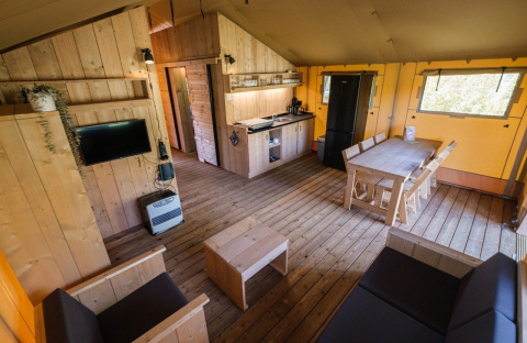 Intérieur d'une tente GlampCamp Safari au Camping De Klimberg, Pays-Bas, avec meubles en bois.