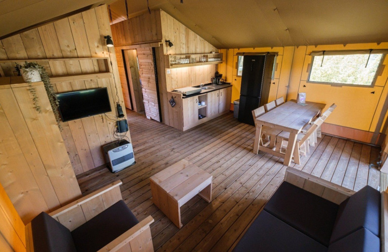 Interieur van een GlampCamp Safari Tent bij Camping De Klimberg, Nederland, met houten meubels.