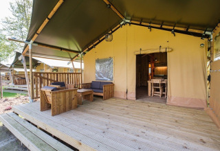 Terraza exterior y entrada de la tienda GlampCamp Safari Tent en Camping De Klimberg, Países Bajos, con muebles de madera.