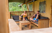 Deux personnes se détendent sur la terrasse d'une tente safari au GlampCamp Safari Tent à Camping De Klimberg, Pays-Bas.