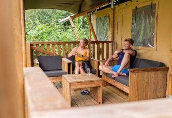Due persone si rilassano sul portico di una tenda safari presso GlampCamp Safari Tent al Camping De Klimberg, Paesi Bassi.
