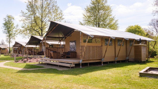 GlampCamp Safari Tent met grote tenten in een groene omgeving, ideaal voor een gezellige glampingervaring.