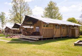 GlampCamp Safari Tent met ruime tenten in een groene omgeving, ideaal voor comfortabel glamping verblijf.