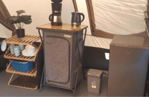 Køkkenområde i en De Waard tunnel telt med hylde, kaffemaskine, elkedel og et lille køleskab.