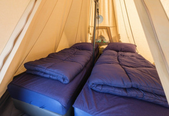 Interieur van een De Waard tunneltent met twee éénpersoonsbedden, blauwe dekbedden en safarisfeer.