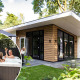 Moderne lodge Silva Wellness med udendørs spa og mennesker, der nyder jacuzzi midt i grøn natur.