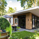 Moderne lodge ved navn Silva Wellness med et spabad i haven, glade gæster nyder afslapning og natur.