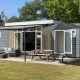 Luksus Chalet med moderne grå og træfacade, terrasse med havemøbler, parasol og stor græsplæne.