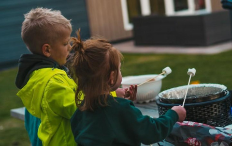 Zwei Kinder rösten Marshmallows draußen beim Luxury Chalet im Recreatiepark De Achterste Hoef, Niederlande.