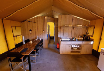 Interno di una tenda safari al Recreatiepark De Achterste Hoef, Paesi Bassi, con zona pranzo e cucina