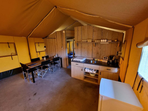 Binnenzicht van een safaritent bij Recreatiepark De Achterste Hoef met een keuken en eettafel.