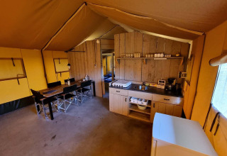 Vista interior de una tienda safari en Recreatiepark De Achterste Hoef con cocina y mesa de comedor.