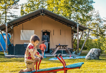 Kinderen spelen op een wip voor een safaritent bij Recreatiepark De Achterste Hoef in Nederland.
