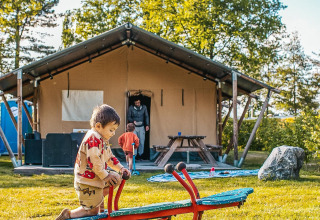 Kinderen spelen op een wip voor een safaritent bij Recreatiepark De Achterste Hoef in Nederland.