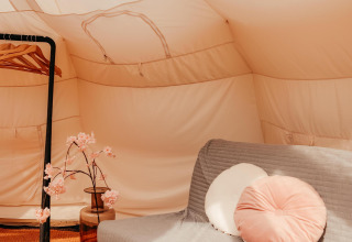 Indretning af Lotus Belle safari-telt på Recreatiepark De Achterste Hoef, med sofa og dekoration.