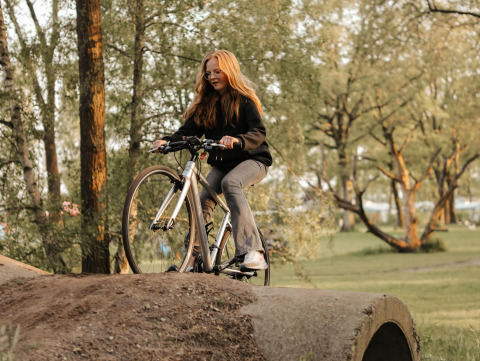Giovane donna in bici su una collina vicino a una tenda Lotus Belle al Recreatiepark De Achterste Hoef.