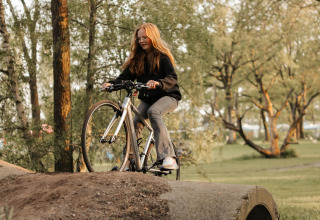 Ung kvinde cykler over en bakke i skoven ved en Lotus Belle safari telt i Recreatiepark De Achterste Hoef.