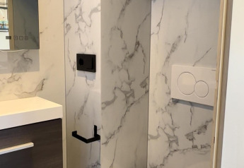 Moderne badeværelse i en hytte med væghængt toilet, marmorvæg og minimalistisk interiørdesign.