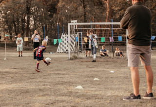 Un niño patea un balón hacia la portería en la cabaña Klapkot, mascotas permitidas, Recreatiepark De Achterste Hoef.