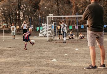 A child kicks a soccer ball towards goal at Klapkot cabin, pets allowed, Recreatiepark De Achterste Hoef, NL.