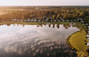 Foto aérea de Waterlodge en Recreatiepark De Achterste Hoef, Países Bajos, con lago, árboles y casas rodantes.