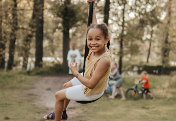 Un bambino allegro si dondola su una zipline al Waterlodge nel Recreatiepark De Achterste Hoef, Paesi Bassi, all’aperto.